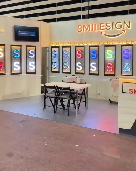 SmileSign stand at C!Print 2026 in Lyon with the illuminated SmileSign logo and a row of lit channel letter samples
