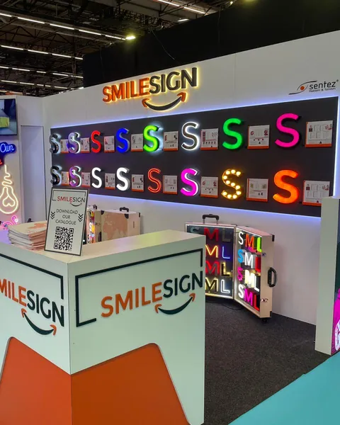 SmileSign stand at FESPA Global Print Expo 2024 in Amsterdam with a wall of illuminated channel letter samples and the SmileSign counter